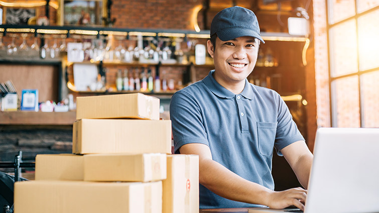 Man working on a laptop next to packages