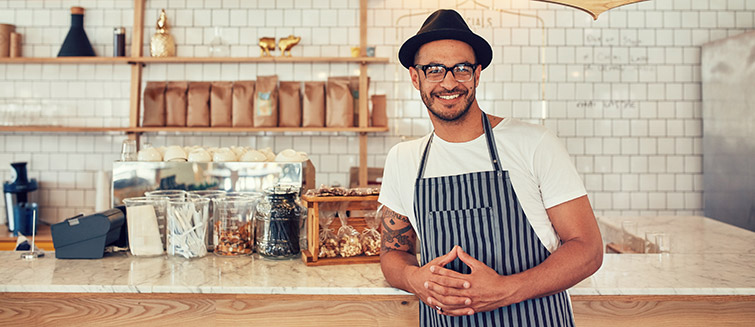 Man wearing apron standing in front of cafe counter