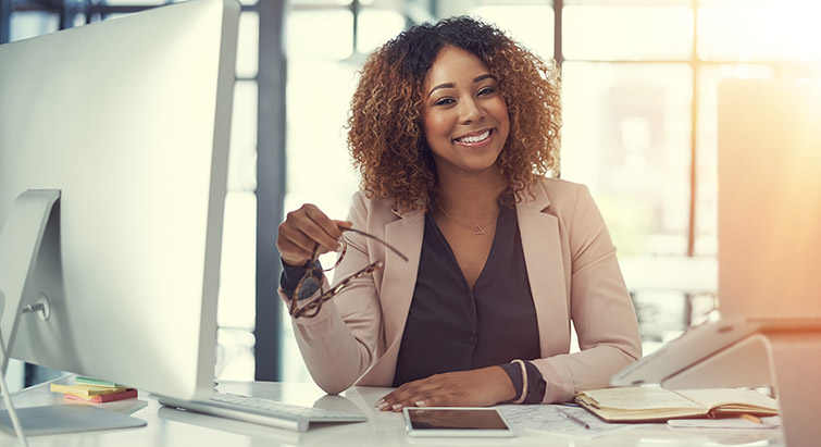 Woman sitting behind office desk, smiling.