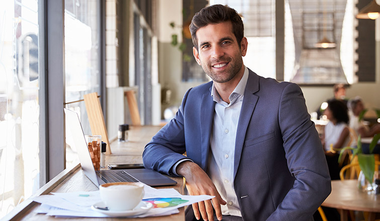 Man working on computer while having a coffee at a cafe