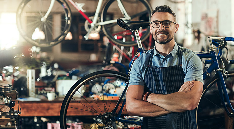 Man wearing apron standing in front of bicycles