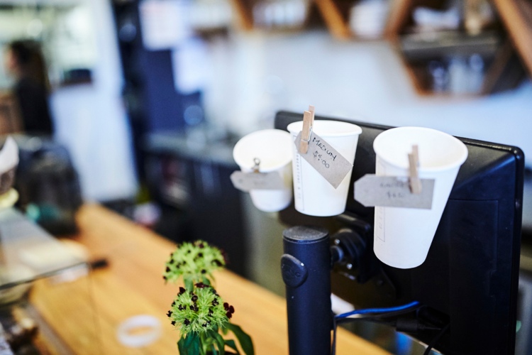 Coffee counter with coffee cups and prices.