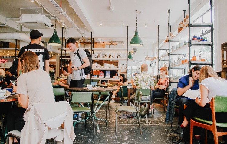 Inside a busy cafe, with people drinking coffee, talking and working.