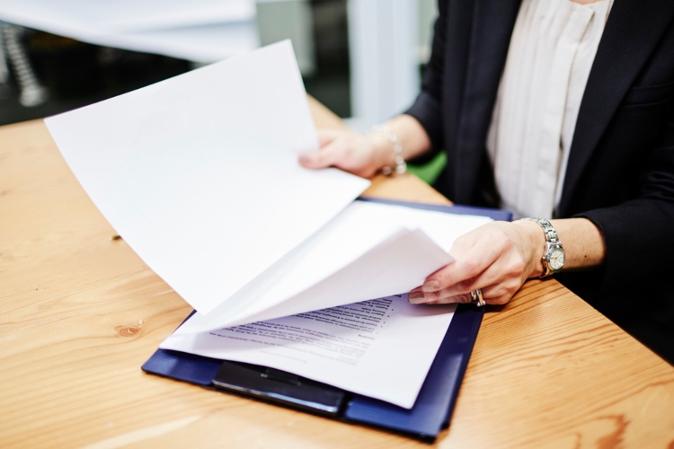 Woman looking over papers attached to a clipboard.