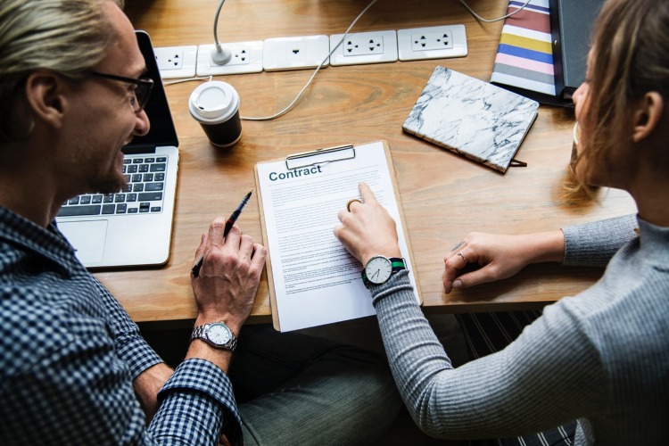 A man and a lady look over a contract document together.